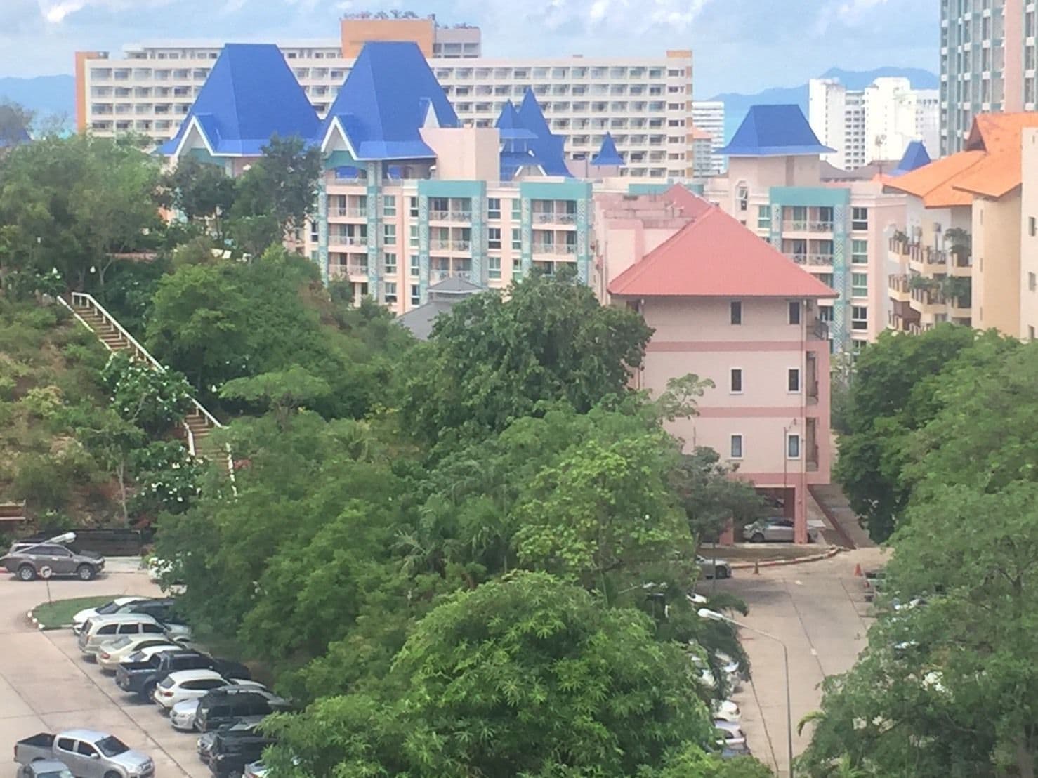 A residential area with multi-story buildings, a parking lot, and a staircase leading up a hill.