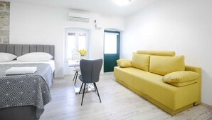 Ein gemütlicher Raum mit einem Bett, einem gelben Sofa, einem kleinen Tisch und einem Stuhl.
