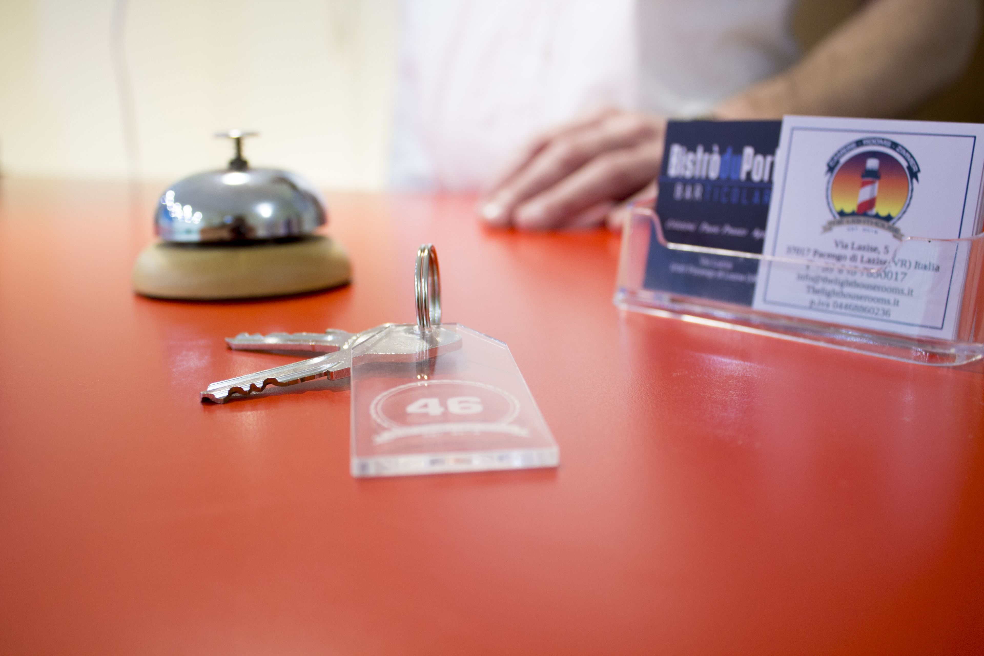 Un comptoir d’accueil d’hôtel avec une cloche, des clés et un présentoir à cartes de visite.