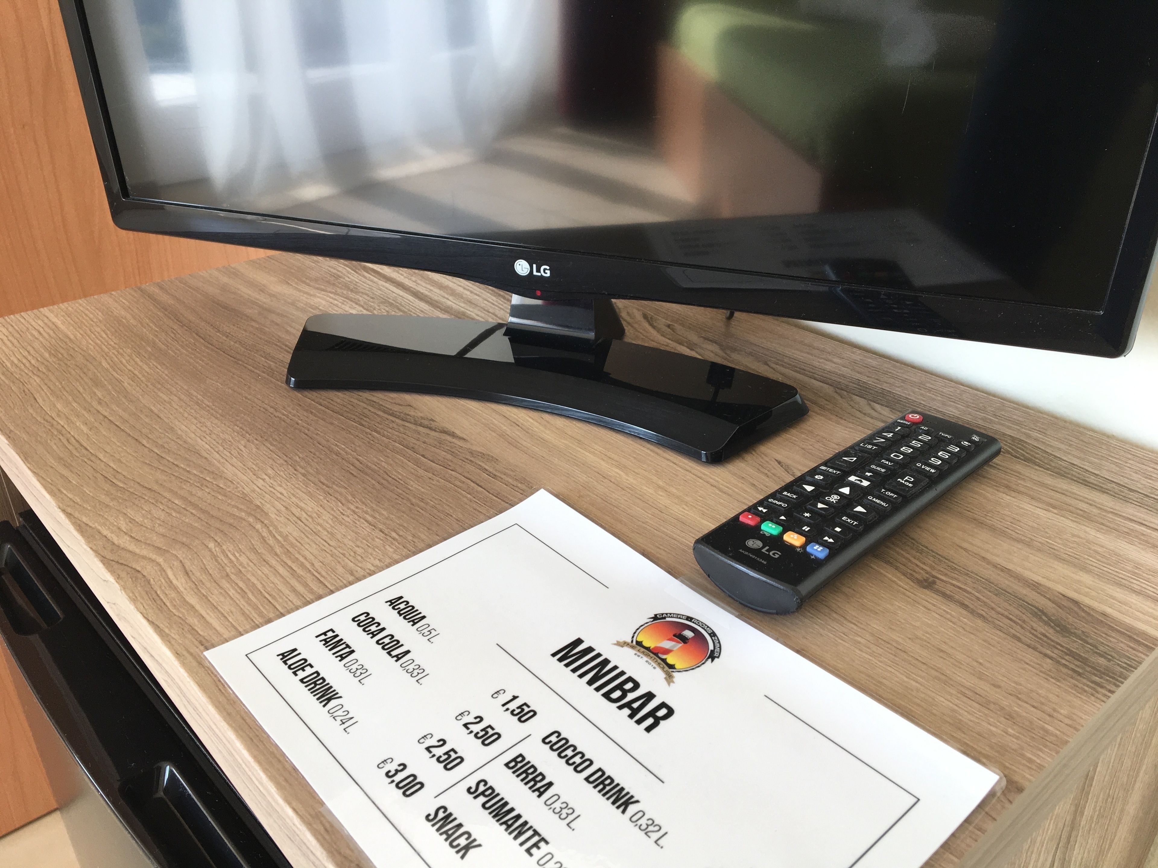 Una mesa de madera con un control remoto, un televisor y un recibo de Minibar.