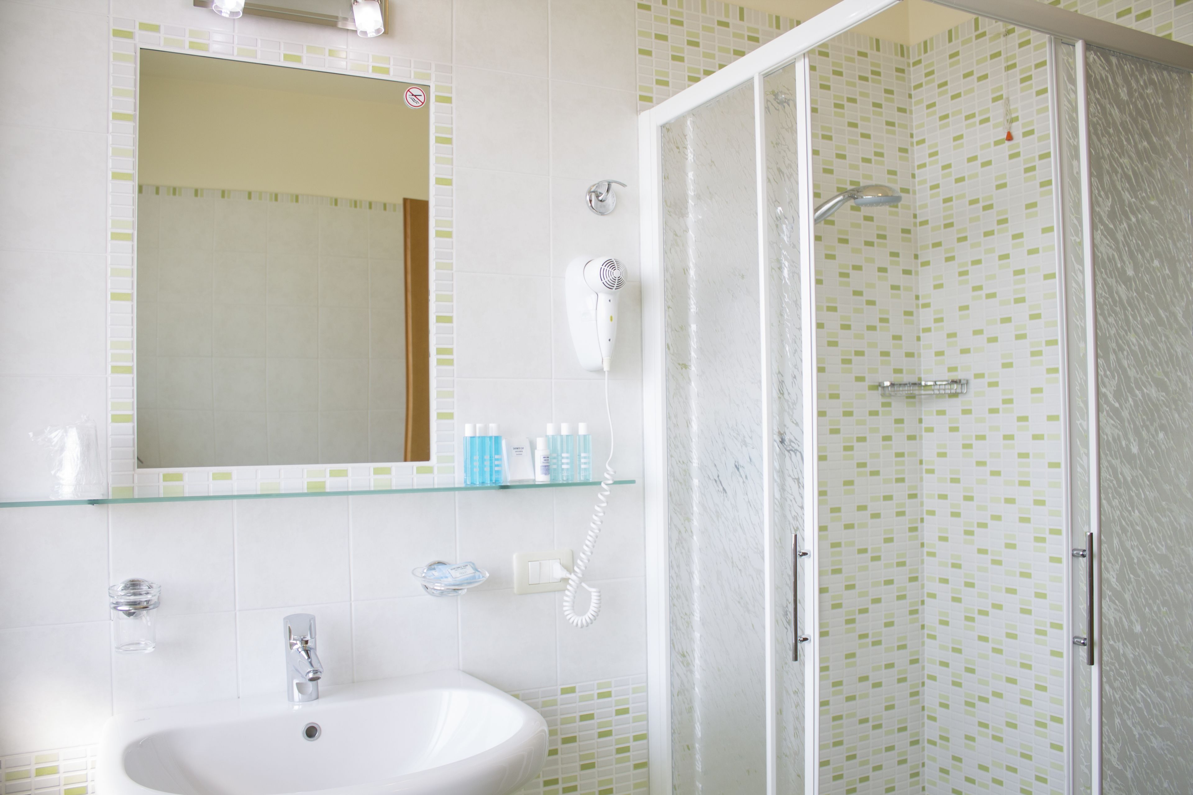 Een badkamer met een wastafel, spiegel en douchecabine met glazen wanden.