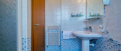 A bathroom with a white sink, a mirror, and a hairdryer mounted on the wall.