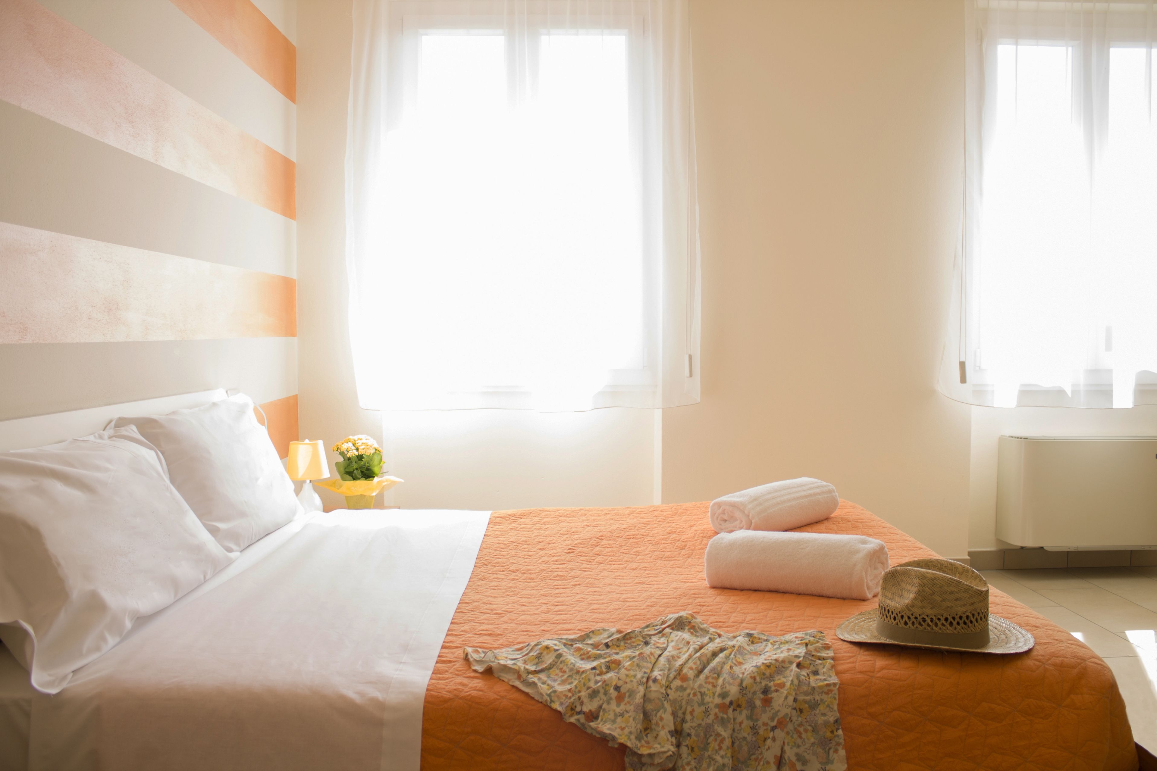 A hotel room with a bed, a nightstand, a window, and a radiator.
