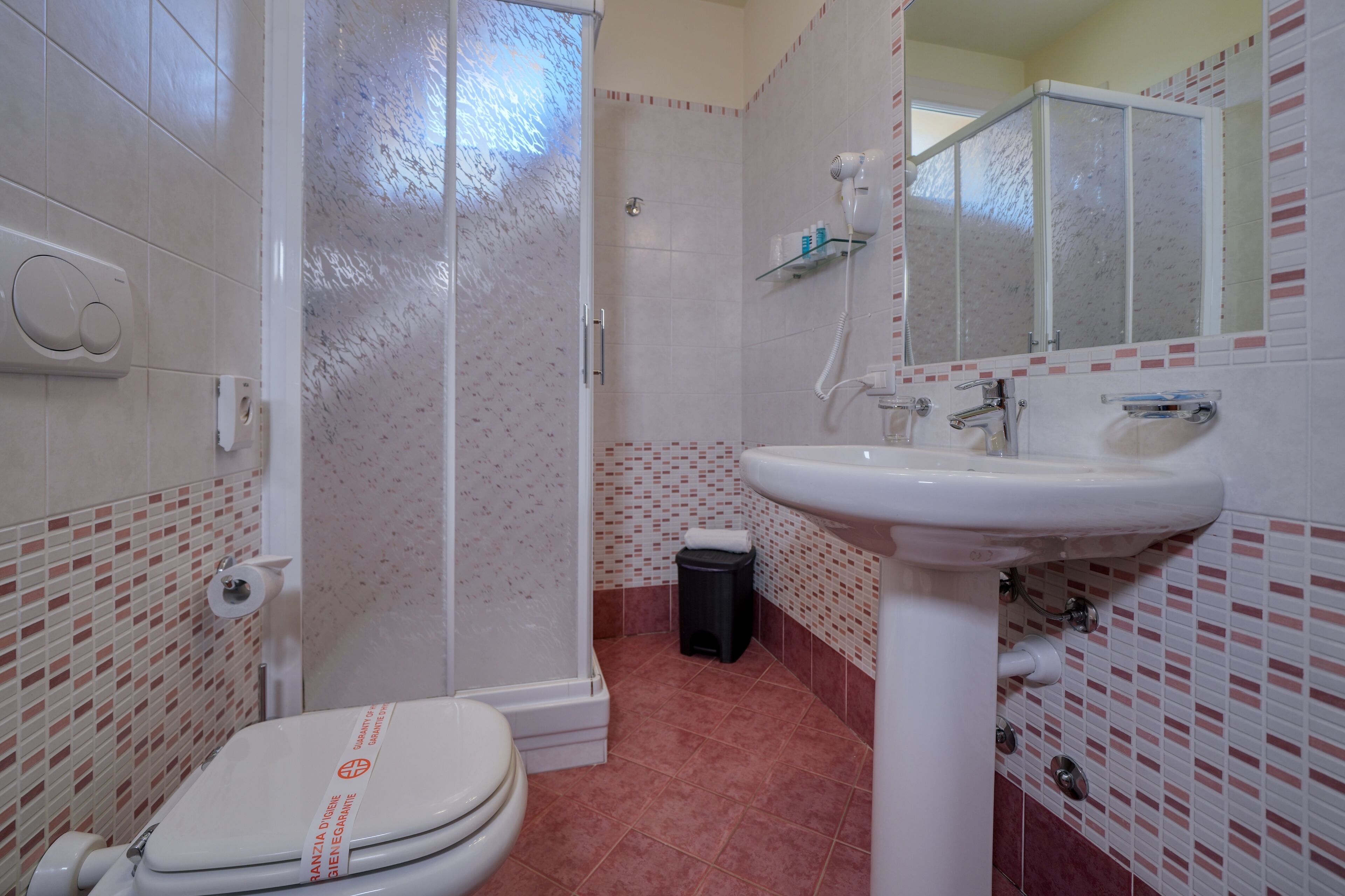Ein Badezimmer mit Toilette, Dusche, Waschbecken und Spiegel.