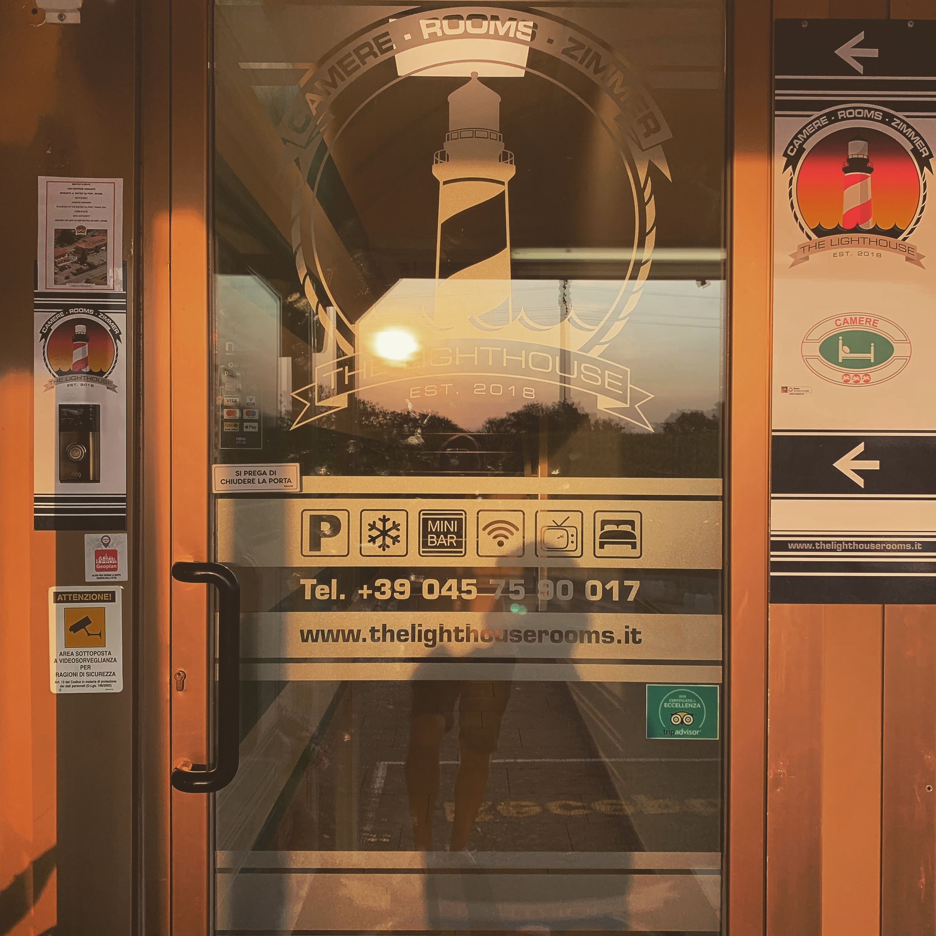 A hotel room door with a glass window, a contact number, and a website address.