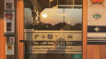A hotel room door with a glass window, a contact number, and a website address.