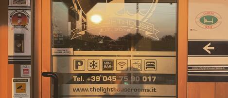Puerta de una habitación de hotel con ventana de vidrio, un número de contacto y una dirección web.