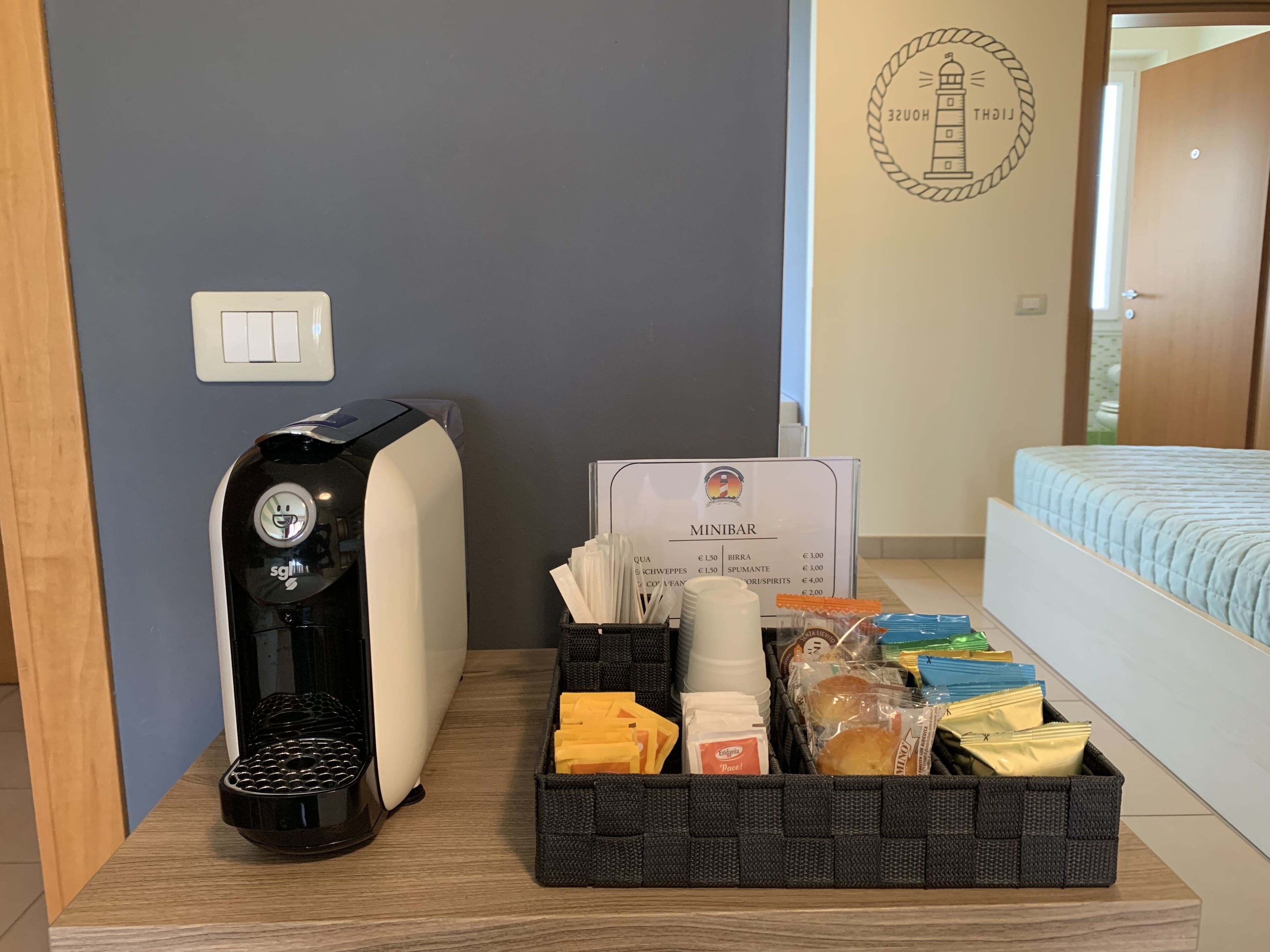 Un miniibar con cafetera, un menú y diferentes aperitivos y bebidas.