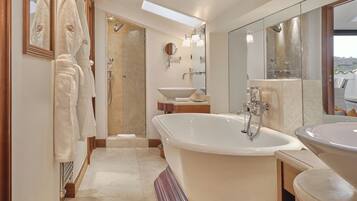 A modern bathroom with a freestanding bathtub, a large mirror, and a walk-in shower.