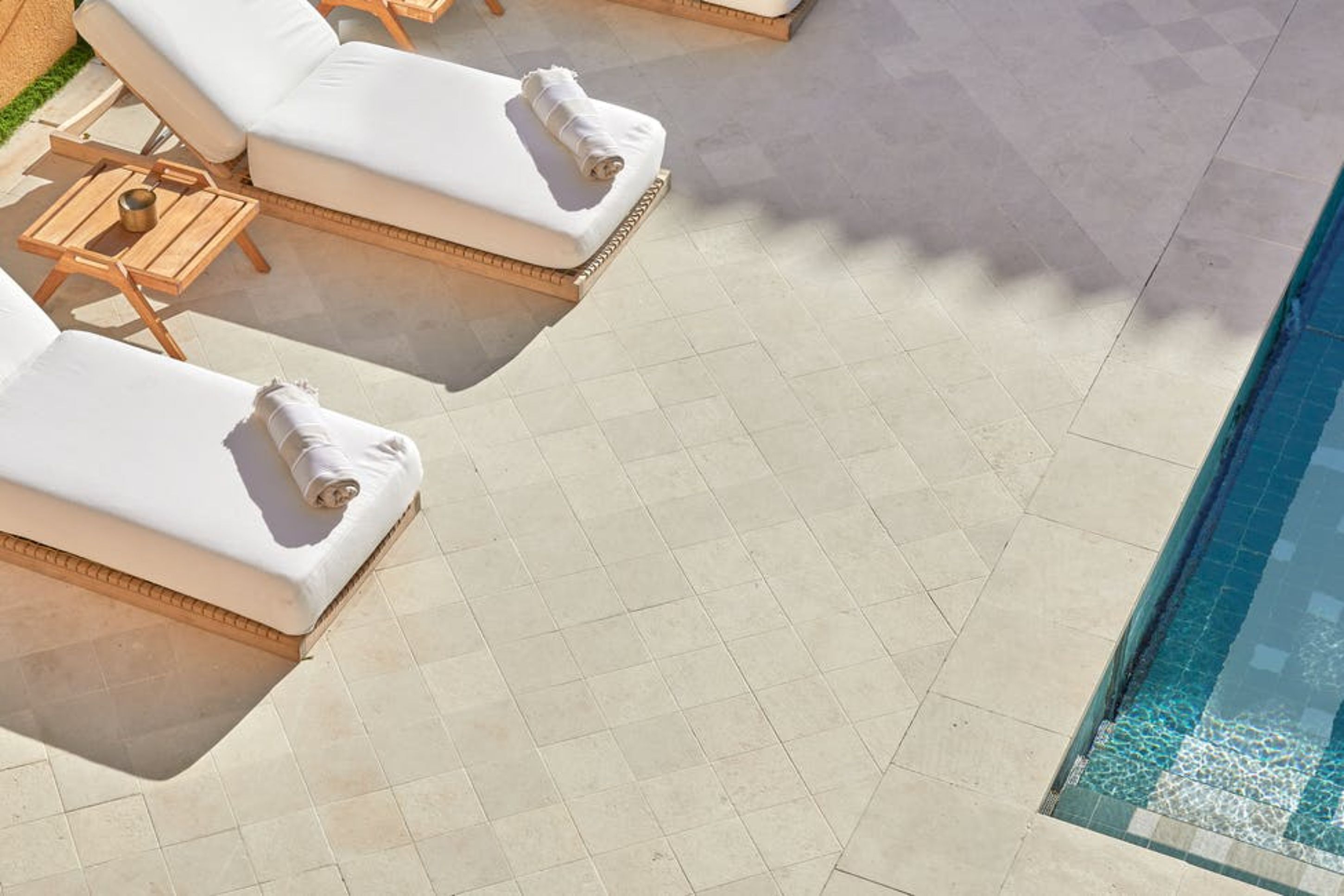 A poolside area with sun loungers and a tiled floor.