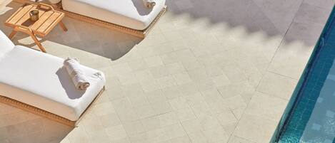 A poolside area with sun loungers and a tiled floor.
