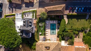 An aerial view of a hotel with a courtyard, parking area, and surrounding buildings. - Airelles Pan Dei Palais (Saint-Tropez)