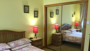 Une chambre avec deux lits, un miroir, des lampes de chevet et une tête de lit en bois.