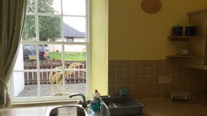 Une cuisine avec une fenêtre, un évier, un lave-vaisselle Bosch et une machine à café.