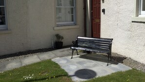 Un banc situé à l’extérieur d’un bâtiment, près d’une porte et d’une fenêtre.
