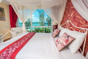 A bed with a canopy, a view of the sea, and a red curtain. - Almali Rawai Beach Residence (Rawai)