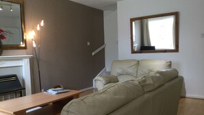 Una sala de estar con un sofá, una mesa de centro, una chimenea y un espejo en la pared.