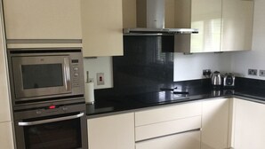 A kitchen with a built-in microwave, oven, and a gas stove. There is a black countertop and white cabinets. - Inverness Apartments - Castlefield (Inverness)
