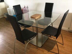 Una mesa de comedor con superficie de vidrio y cuatro sillas negras.