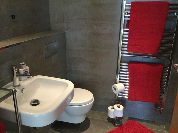 Une salle de bain avec un lavabo blanc, des toilettes et un porte-serviettes avec des serviettes rouges.