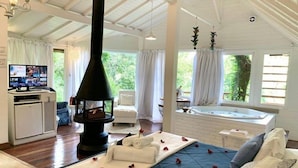 A cozy room with a fireplace, a television, a sofa, and a bathtub. - Pousada Solar d'Araucária (Gonçalves)