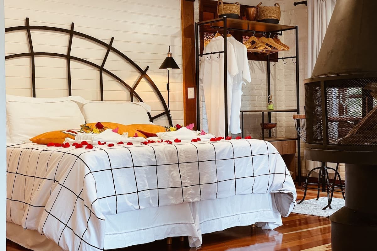 Une chambre à coucher avec un lit, une tête de lit en bois, un portant à vêtements et une cheminée.