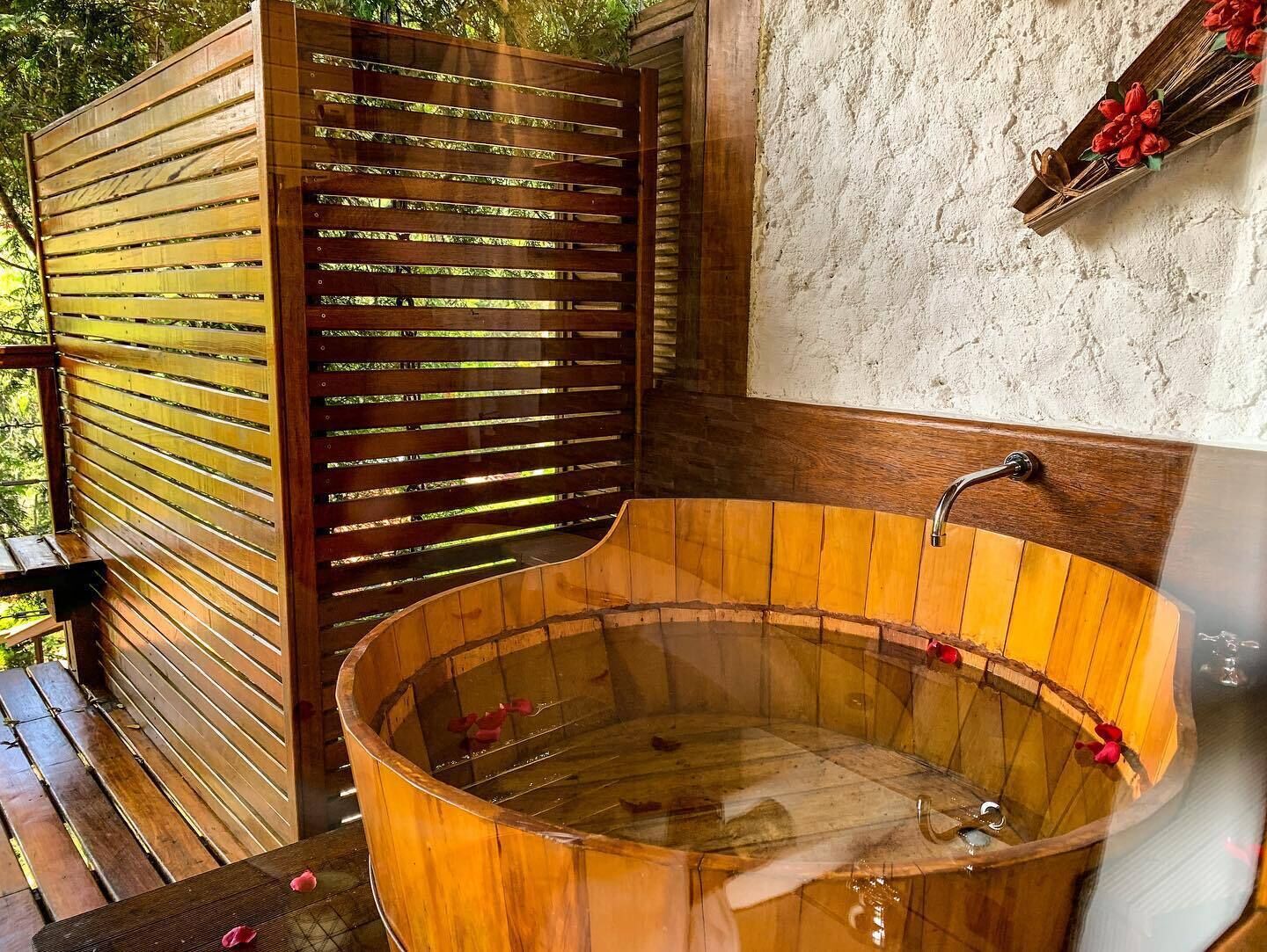 Una bañera de madera con un banco de madera y una valla de madera.