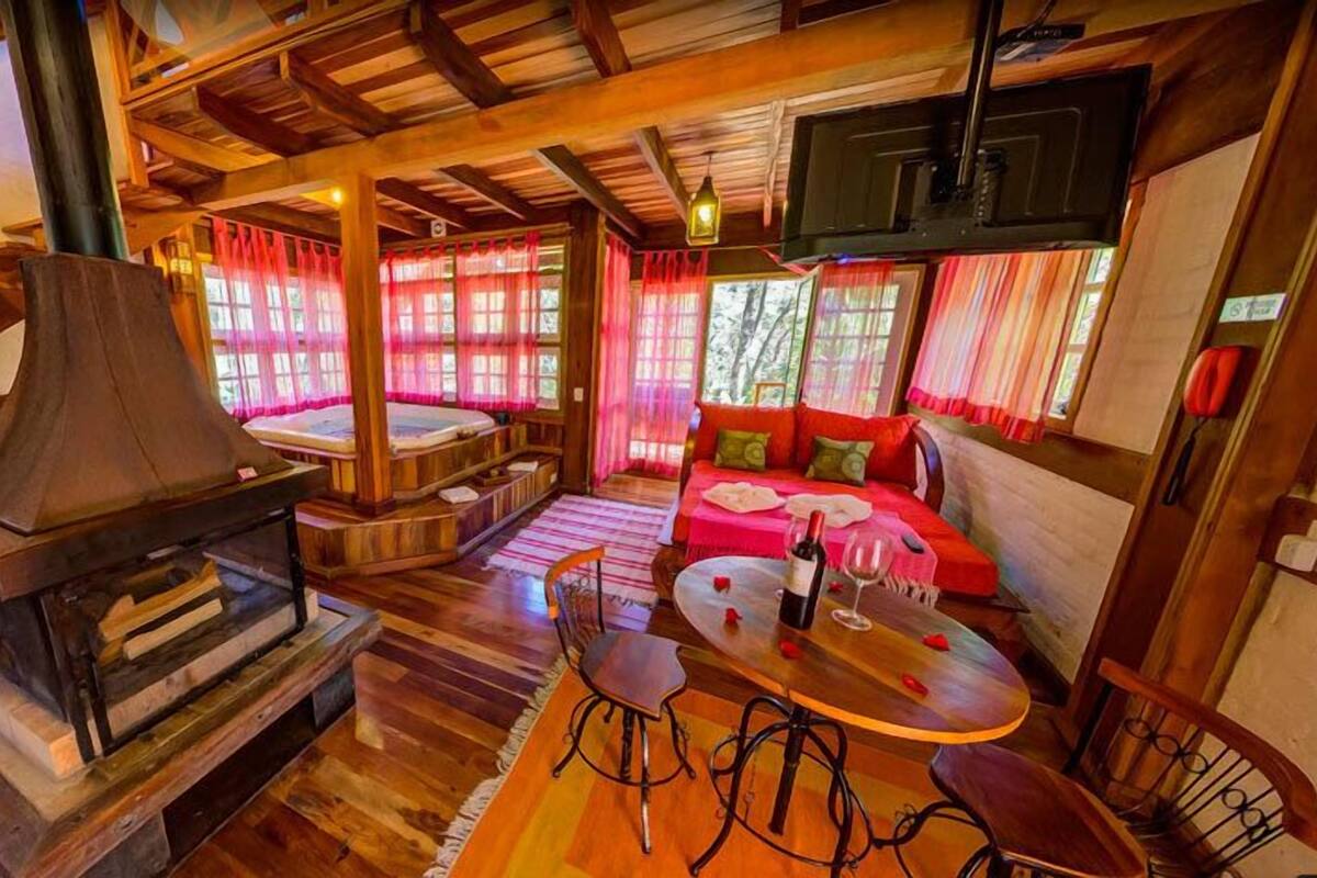 Un intérieur de chalet chaleureux avec une cheminée, un ensemble de canapés et un coin repas.