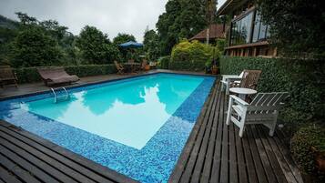 Ein rechteckiger Pool mit einer Fliesenbordsteinkante, umgeben von einer Holzdielen-Terrasse.