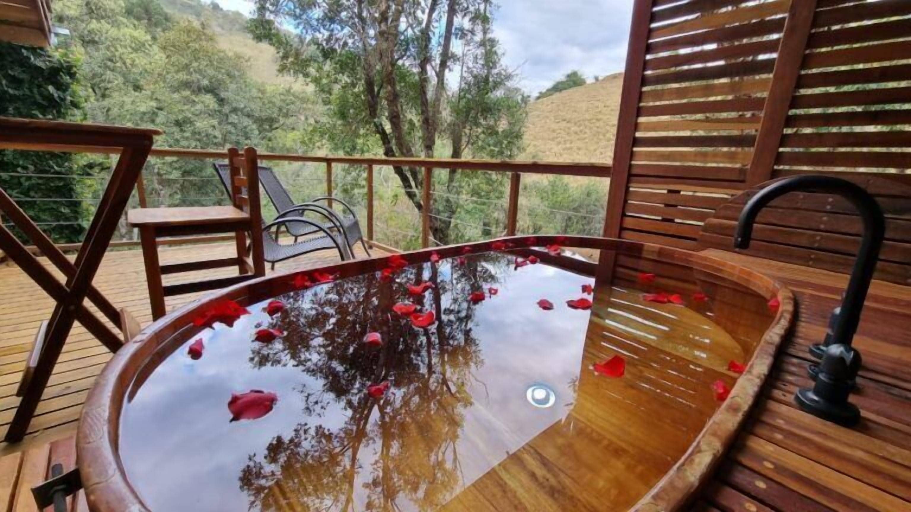 A wooden deck with a hot tub surrounded by chairs and a wooden fence.