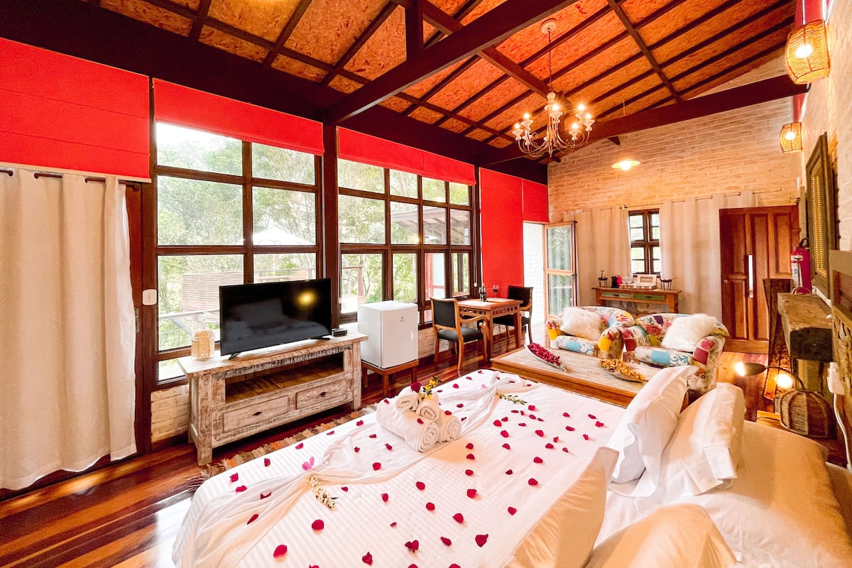 Une chambre spacieuse avec un grand lit, une télévision et un coin repas.