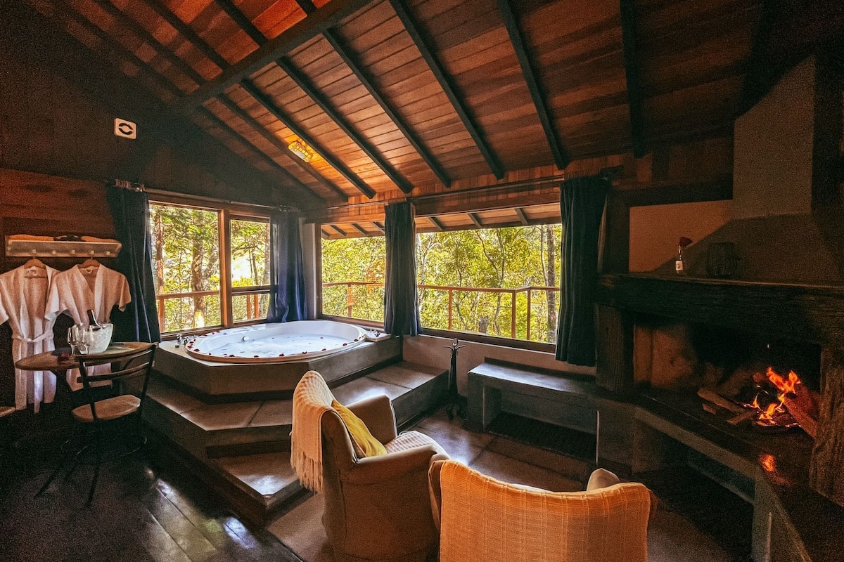 Un intérieur de chalet chaleureux avec un jacuzzi, un coin salon et une cheminée.
