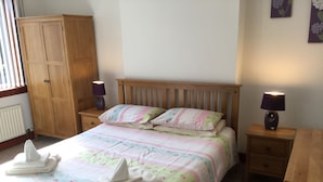 A bedroom with a bed, two bedside tables, a wooden wardrobe, and a window. - Inverness Apartments - Culduthel (Inverness)