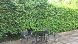 A patio with a round table and four chairs, surrounded by a hedge. - Inverness Apartments - Culduthel (Inverness)