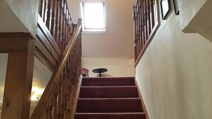 A wooden staircase with a red carpet, a small table with a lamp, and a window at the top.