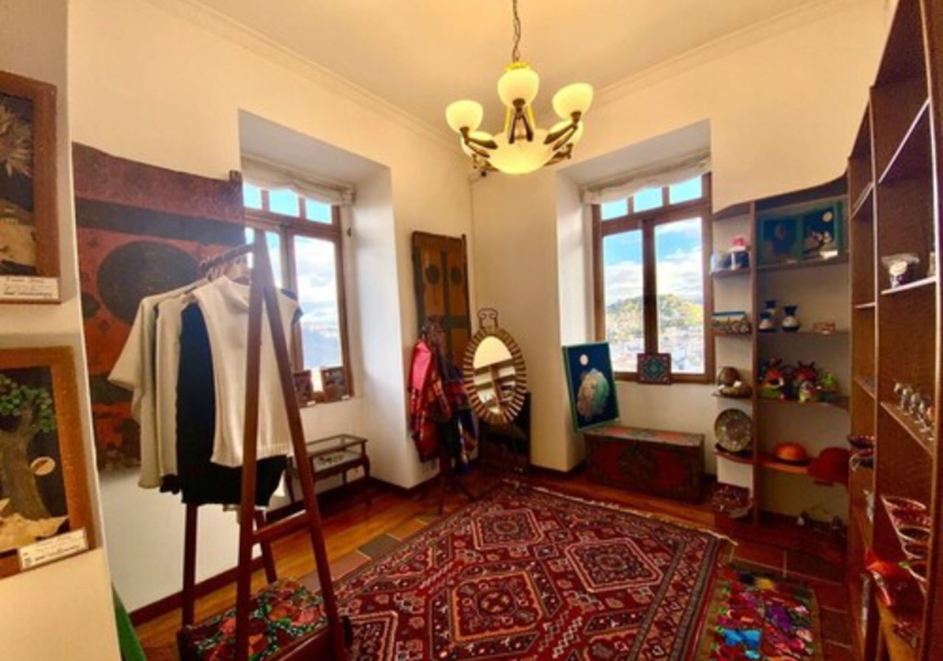 A room with a large rug, a wooden easel, and various artworks on the walls.