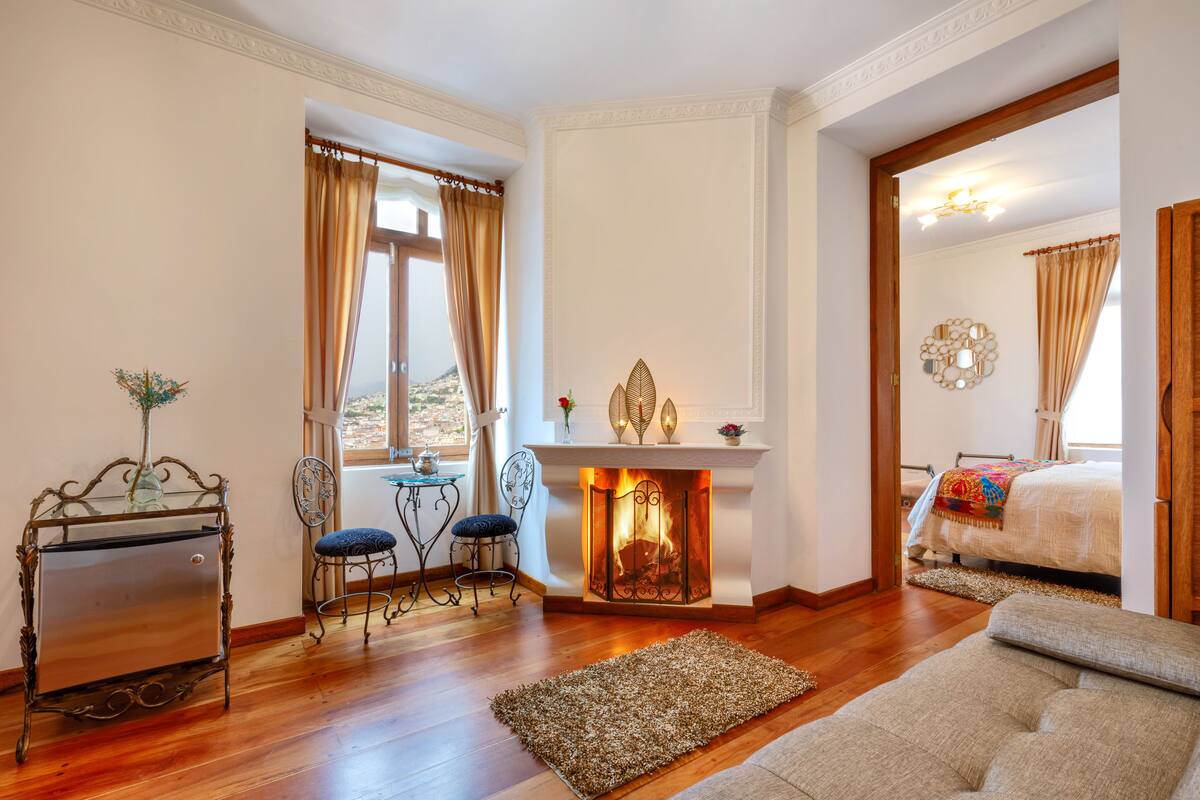 Een knus ingerichte kamer met een open haard, een bed, een bank en een eethoek met stoelen en een tafel.