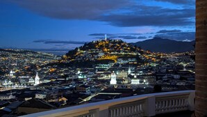 Un paisatge urbà nocturn amb edificis il·luminats i un turó destacat amb una església al capdamunt.