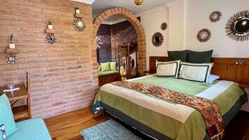 A bedroom with a brick wall, a wooden bed, a green bedspread, and decorative wall mirrors.