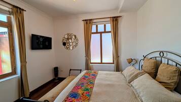 A neatly arranged bedroom with a bed, a bedside table, a lamp, and a wall-mounted TV.