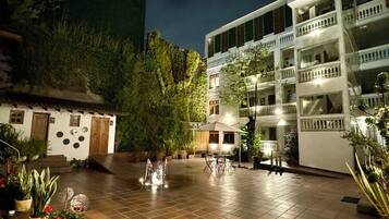 Un patio con una fuente, asientos al aire libre y un edificio con balcones.