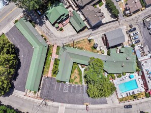 Vista aérea de una propiedad que cuenta con piscina, estacionamiento y edificios con techos verdes.
