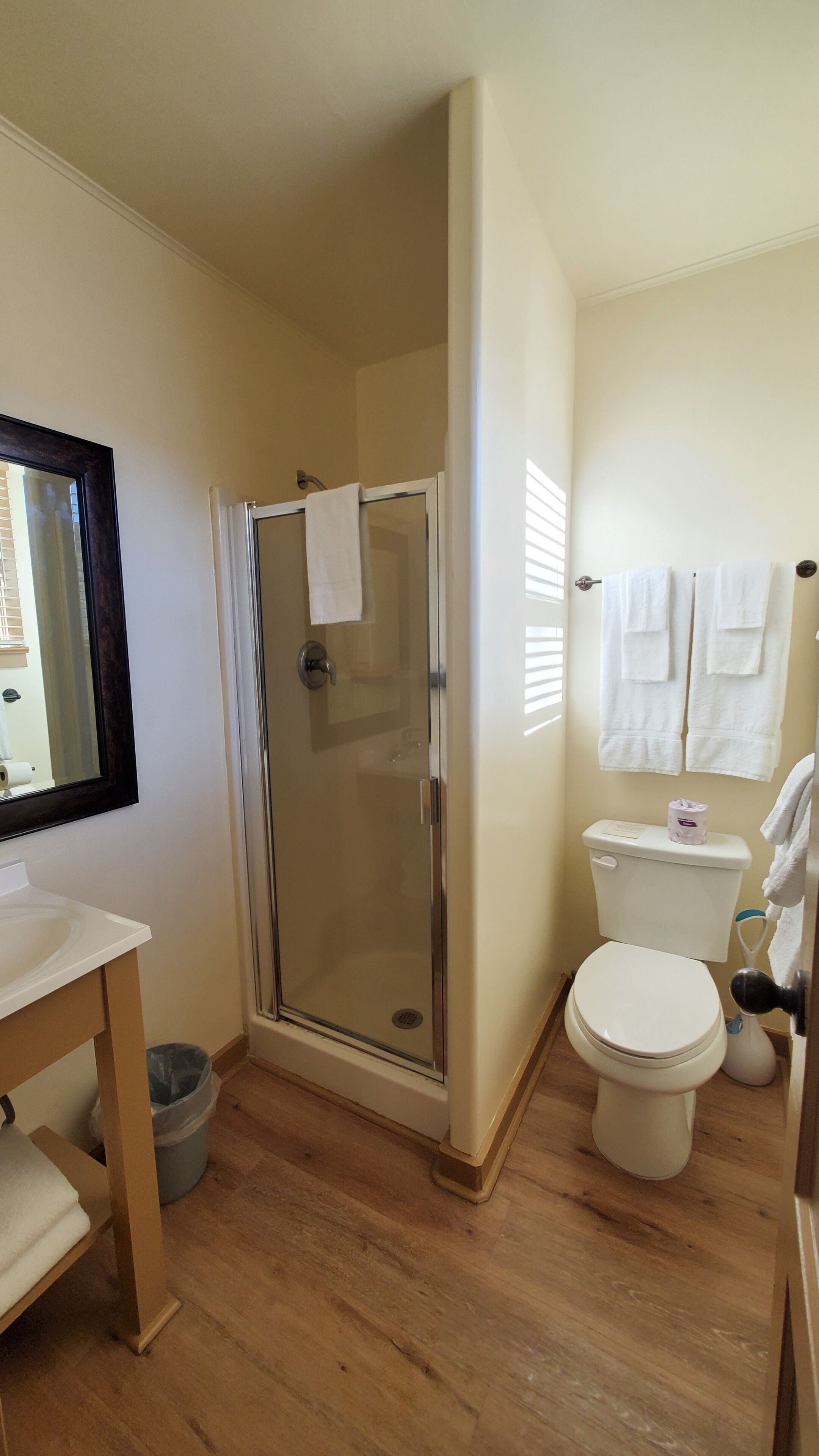 A bathroom with a glass-enclosed shower, a toilet, and a sink.