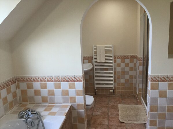 A bathroom with a bathtub, toilet, and shower area. - Inverness Apartments - West Heather (Inverness)
