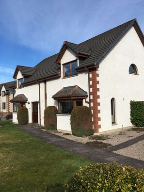 A row of houses with pitched roofs, white walls, and brick accents. - Inverness Apartments - West Heather (Inverness)