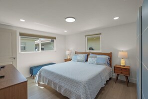 A bedroom with a bed, bedside tables, a bench, and a desk.