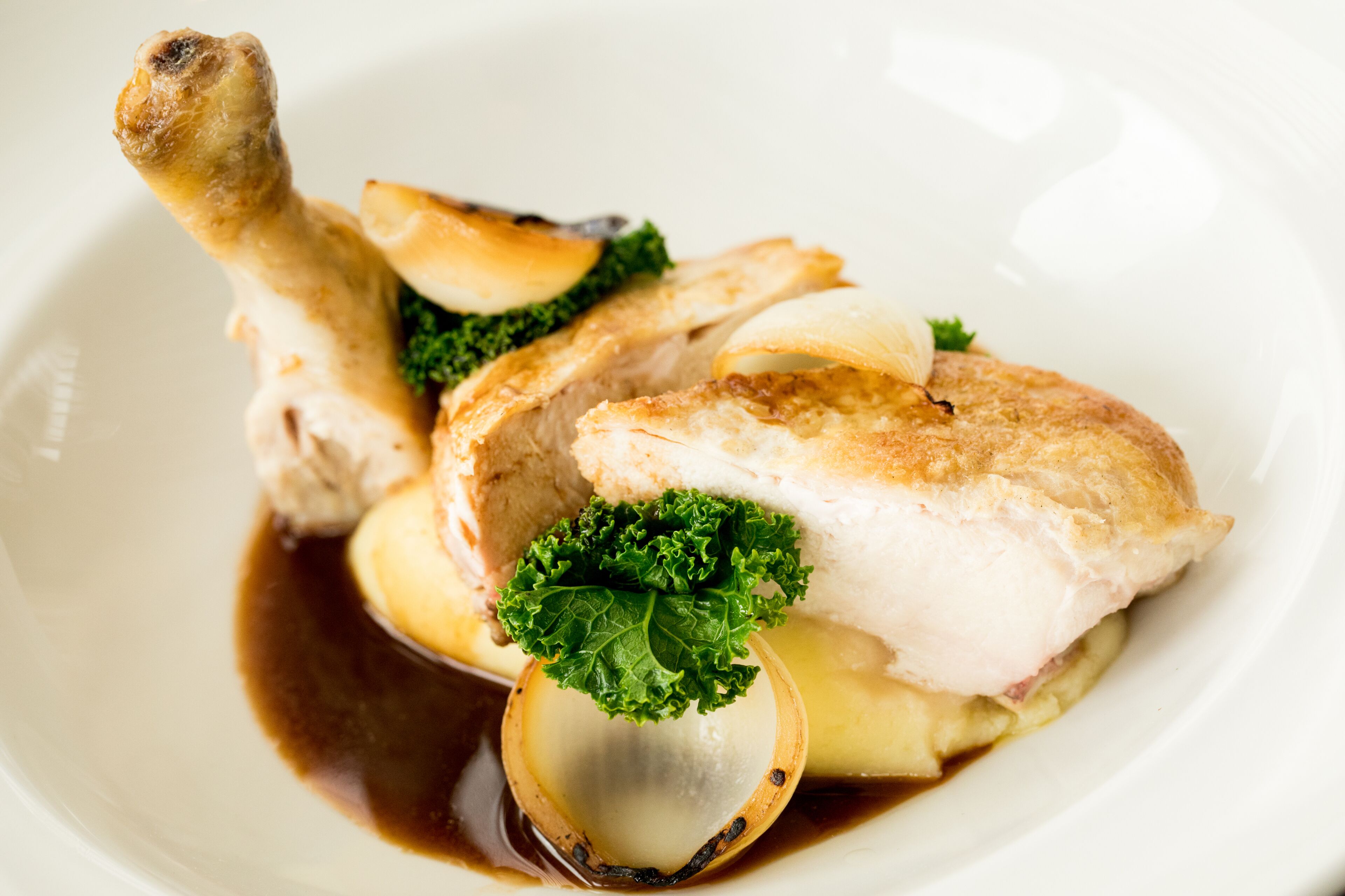 A plate with a piece of meat, a clamshell, and some greens.
