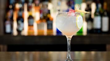 A cocktail glass with a lemon slice and a cherry on a bar counter.