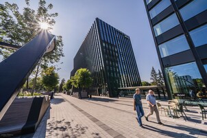 A modern urban plaza with a tall building, benches, and outdoor seating areas.