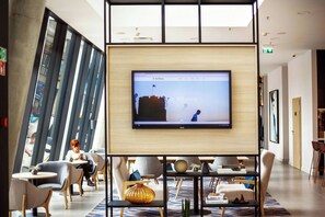 Un interior moderno con una pantalla grande mostrando un sitio web, asientos cómodos y un suelo con diseño.